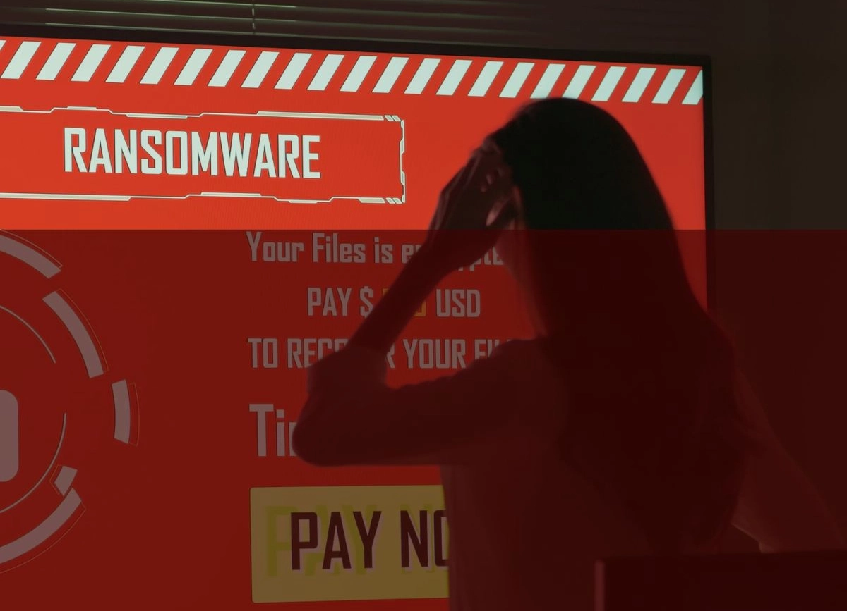Worried woman in shadow staring at a screen that says ransomware. 